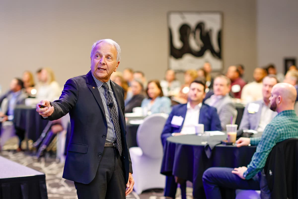 Speaker presenting to a seated audience at a conference luncheon